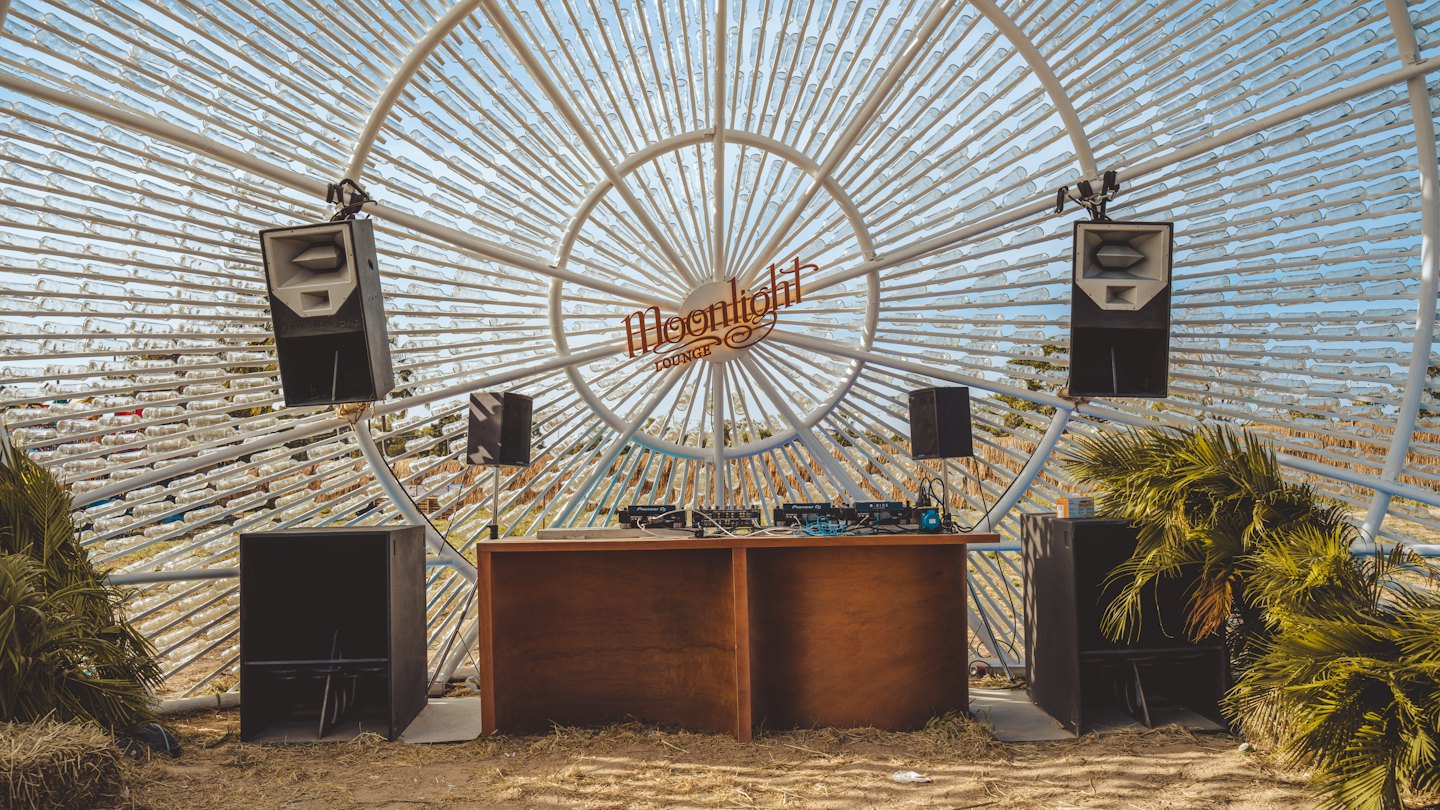 DJ equipment sits under an arch of recycled plastic bottles.