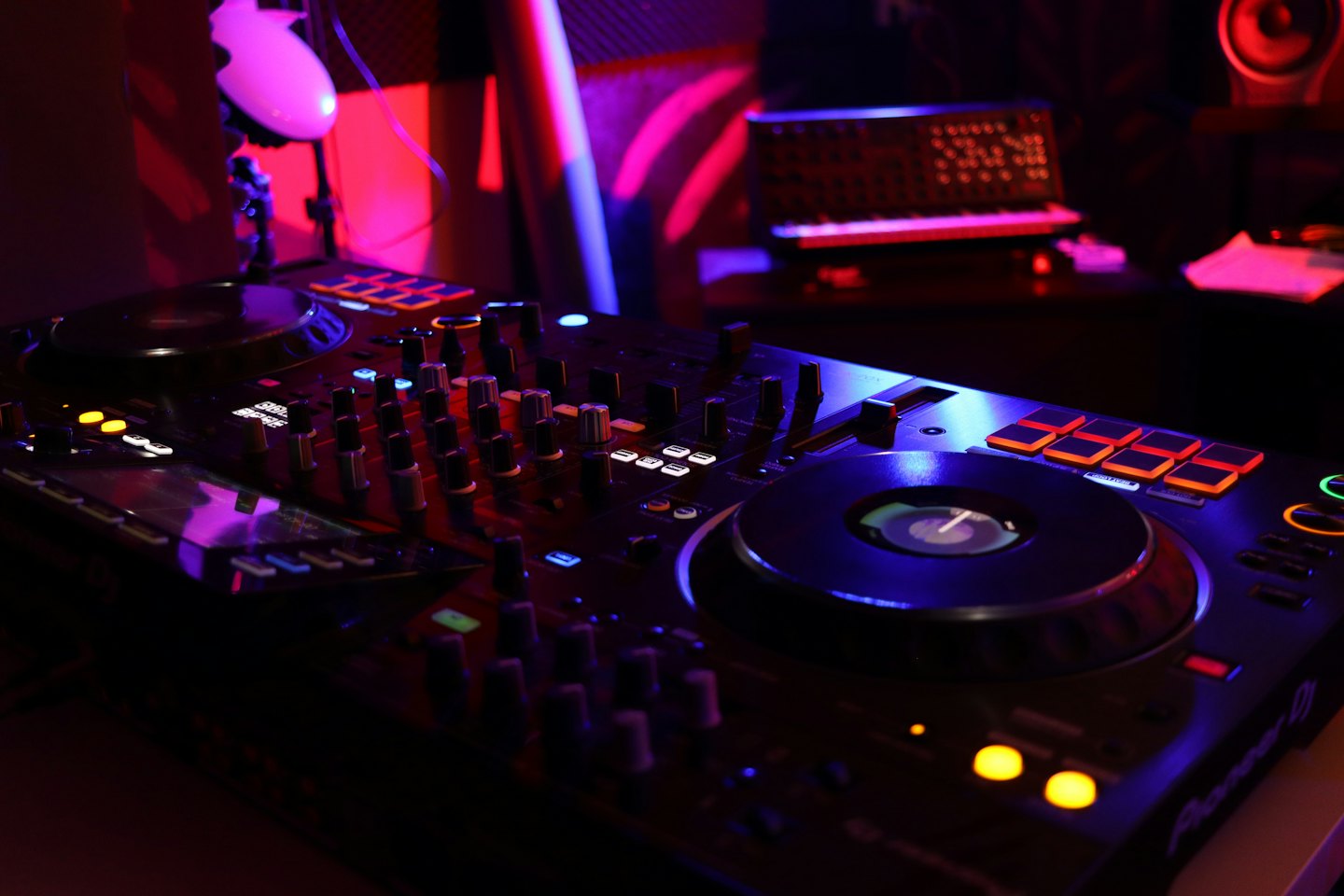 DJ controller with glowing buttons and colorful lights.