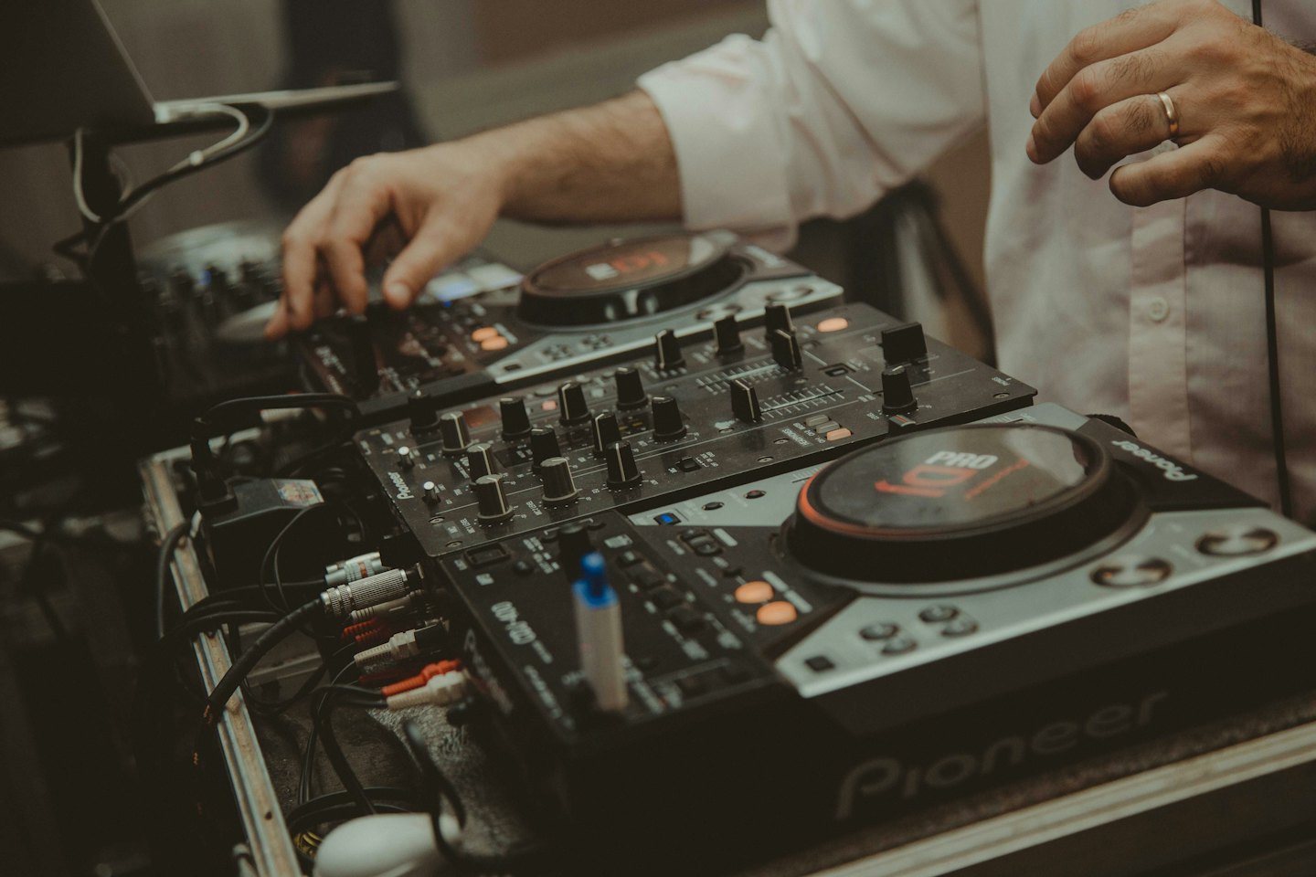 Hands operating DJ turntables and mixer.